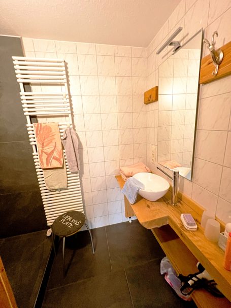 Badezimmer mit Waschbecken, Spiegel, Handtüchern und einer begehbaren Dusche